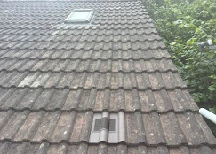 The roof of a house with a broken window.